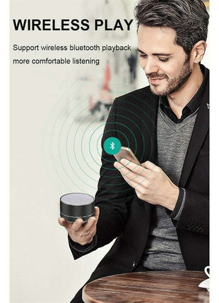 Man using Wireless Bass Bluetooth Speaker with smartphone, showcasing portable design and wireless playback for handsfree audio experience.