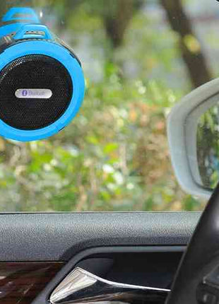 Waterproof Mini Speaker with Bluetooth and mic suctioned to car window, ideal for hands-free calls and music on the go. Compact and travel-friendly design.